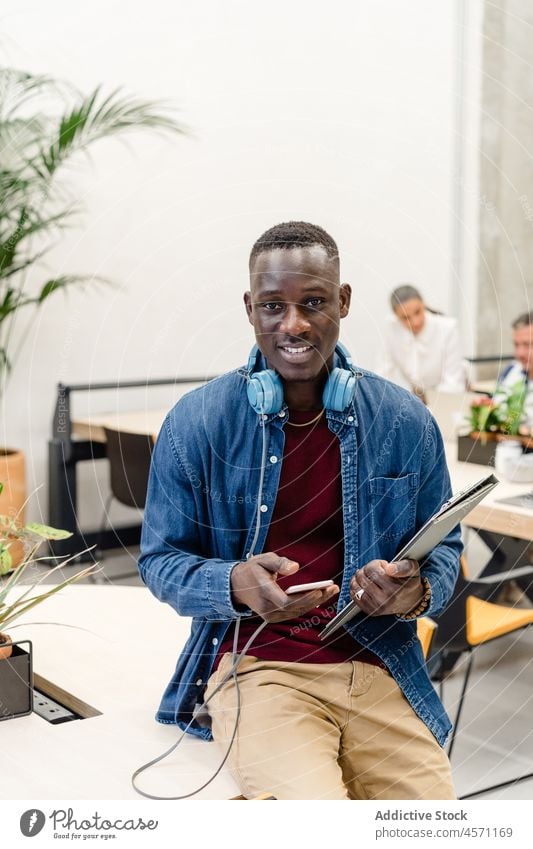 Cheerful black man browsing smartphone near colleagues businesspeople work online coworker office company tablet workplace collaborate workspace occupation