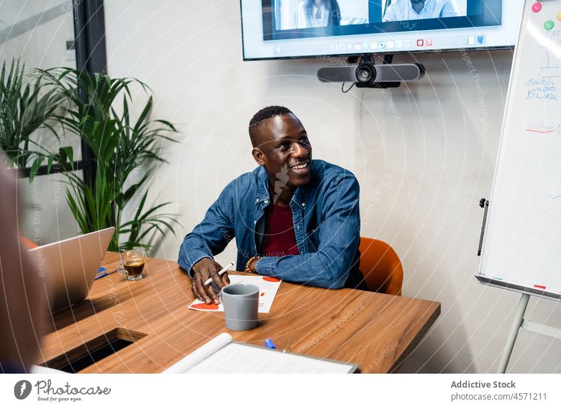 Cheerful black man sitting at table in office work worker company employee paperwork document workplace occupation male workspace desktop modern career