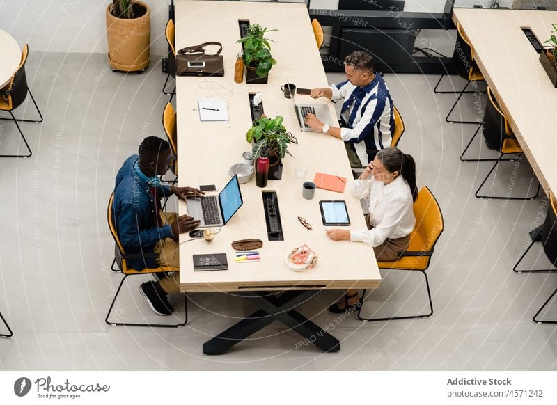 Group of multiracial colleagues working on laptops businesspeople browsing tablet open space online coworker office company workplace collaborate workspace