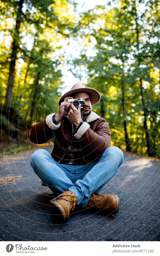 Man taking photo while sitting on road man tree path photo camera take photo photographer nature grove recreation style portrait adventure trip leisure outfit