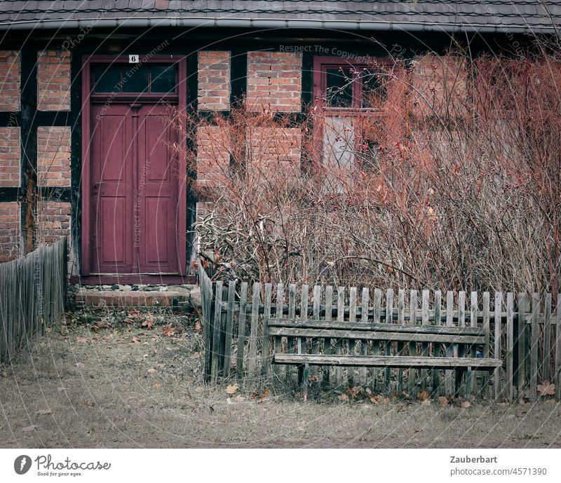 Bench in front of wooden fence and half-timbered facade with door in red-brown Fence Wooden fence Wooden bench Half-timbered house brick Red Brown Sit