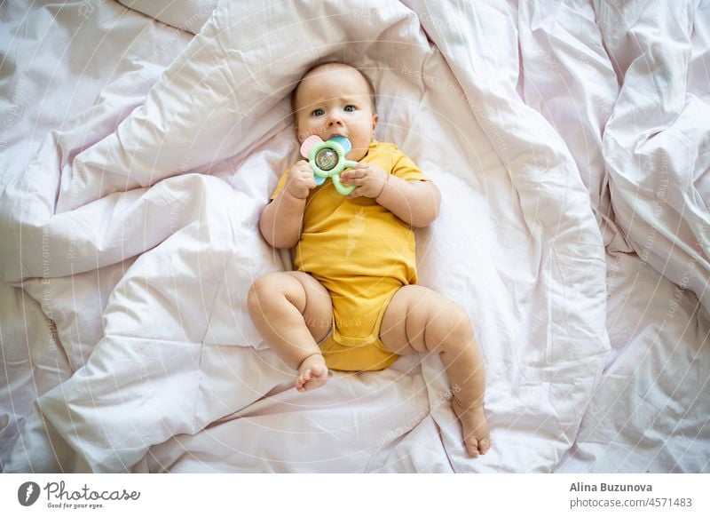 Caucasian blonde baby seven months old lying on bed at home. Kid wearing cute clothing yellow color newborn infant Illuminating child ultimate gray kid