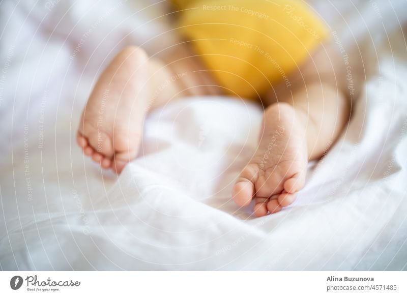 Baby's feet closeup. Caucasian baby seven months old sleeping on bed at home. Kid wearing cute clothing yellow color newborn infant child kid interesting learn