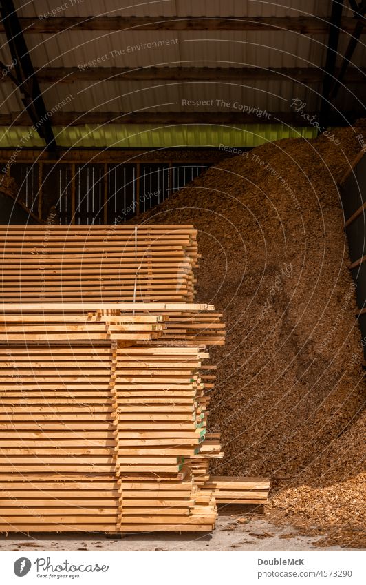Stacked wooden slats lie in front of a huge pile of wood chips Wood stacking Wood shavings sawdust Collection Logging Heap Wooden boards Woody