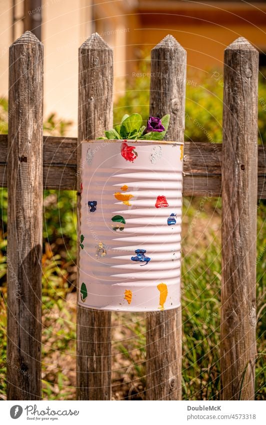 Painted, decorated tin can as a flower pot hanging on the garden fence Tin Flowerpot Wooden fence Garden fence lattice fence Fence naturally Exterior shot