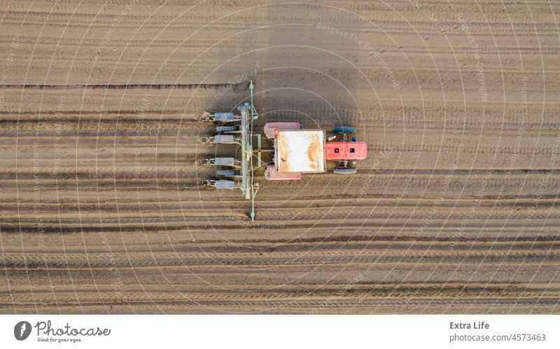 Aerial top view of tractor as dragging a sowing machine over agricultural field, farmland Above Agricultural Agriculture Arable Cereal Corn Cornfield Country