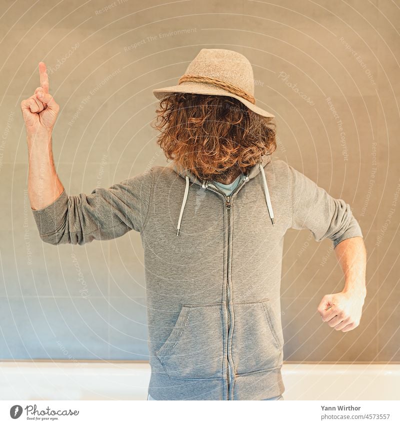Man with hat and long curly brown hair on face points finger upwards Hair on the face long hairs Facial care Face Hat Jacket Resolve Self-confident