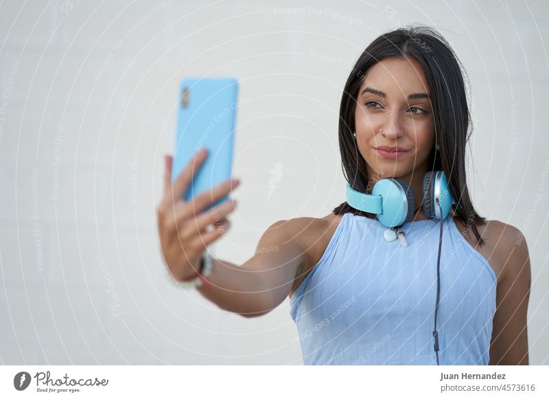 beautiful woman takes a selfie with the smartphone with the headphones on her neck young mobile phone cellphone mobilephone cellular telephone smart phone photo