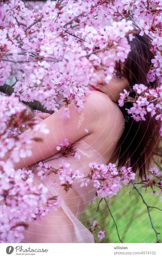sensual, seductive, portrait of a sexy, young, brunette woman in pink dress in pink flower tree blossoms in spring awakening, sakura, copy space flowers relax