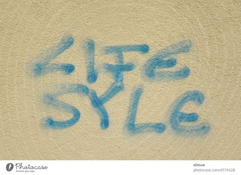 LIFE SYLE is written in blue letters on the plastered wall / english - spanish / graffito life system Lifestyle Syle Spanish Graffito Graffiti spelling mistakes