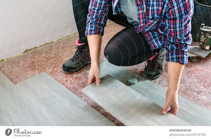 Female bricklayer placing tiles to install a floor unrecognizable female tiler woman closeup detail copy space crouched construction home worker repairing mason