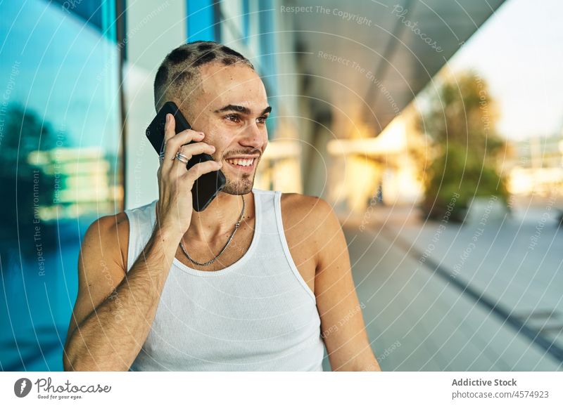 Smiling eccentric man talking on smartphone using phone call positive speak chat communicate style male conversation cellphone optimist enjoy young gadget