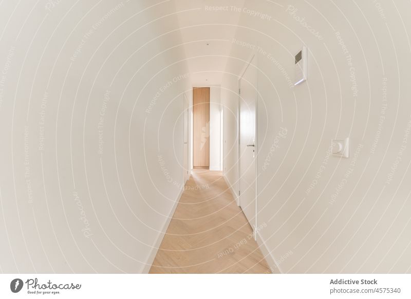 Empty corridor with white walls and door and parqueted floor hallway narrow empty interior entrance simple residential minimal daylight doorway wooden dwell
