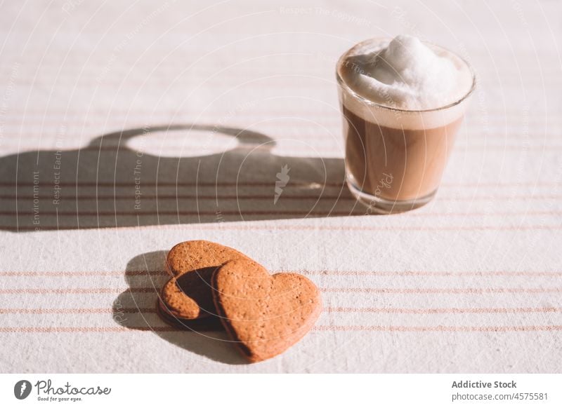 Glass of foamy coffee with heart shaped biscuits served on table latte macchiato cookie dessert drink delicious tasty sweet glass food love milk froth mocha