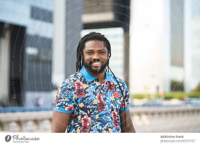 Black man shaking hair on street carefree dreadlocks smile urban modern style freedom cool pastime apparel outfit happy reflection male african american black