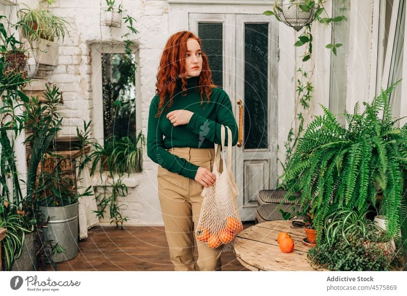 Woman with reusable string bag of tangerines in garden woman zero waste houseplant botanic vegetate botany cultivate female grow at home foliage reduce reuse