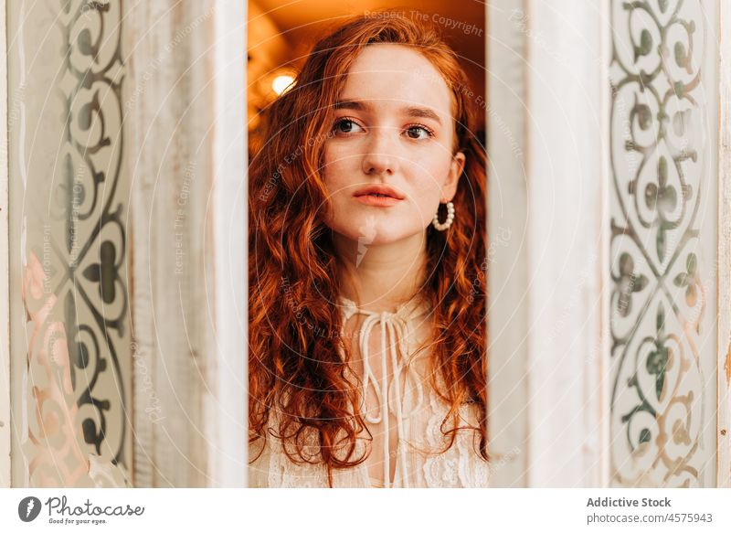 Woman framed between two doors woman enter open garden red hair fresh long hair young grow stand wavy hair looking away indoors doorway hobby personality