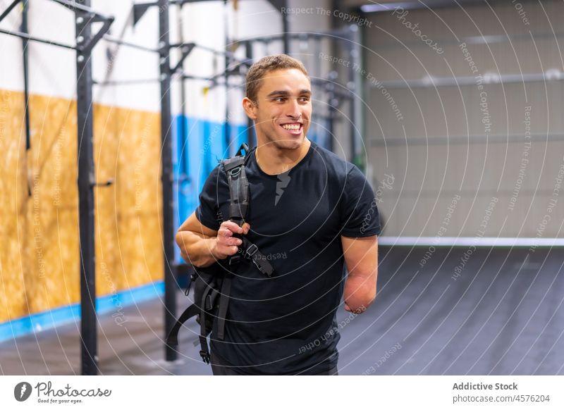 Happy male amputee on gym man smile handicap casual modern portrait cheerful disable garage optimist glad positive joy young backpack carefree happy satisfied