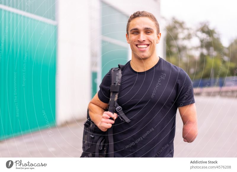 Happy male amputee on street man smile handicap urban casual modern summer portrait cheerful disable optimist glad positive joy daytime young guy backpack