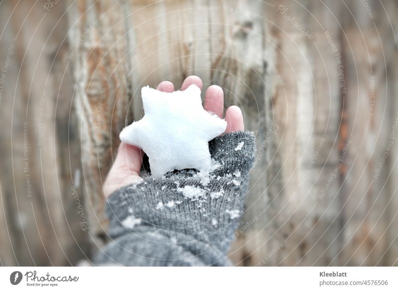 I give you a star for Christmas - woman hand with grey glove holds a star made of snow and ice Stars ice and snow Women`s hand Gray gloves