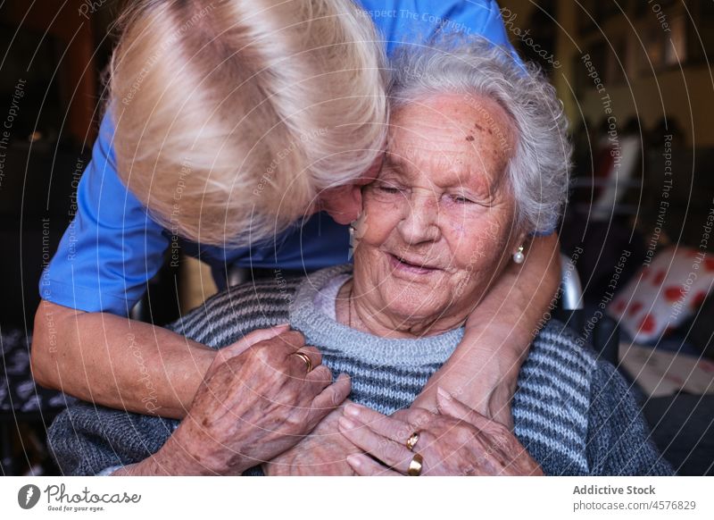 Nurse hugging aged woman in room nurse elderly patient help kiss care love support disable pensioner old specialist affection home apartment retire embrace