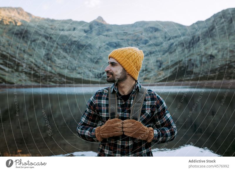Man with cap and gloves in the mountains man hiker water shore tourist lake journey waterside nature ridge stone rough formation coast rocky waterfront festive