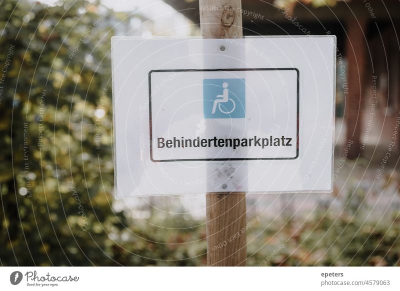 A laminated sign that says Behindertenparkplatz / disabled person parking space in German ableism access behindertenparkplatz blue concept disability german