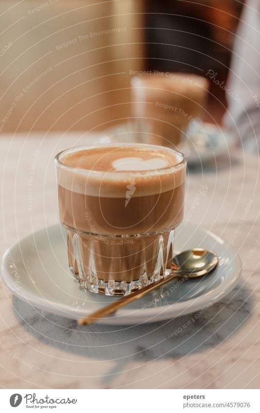 Glass cup with frothy milk coffee drink on a saucer on a table aroma background beverage breakfast brown cafe caffeine cappuccino cream espresso foam glass hot