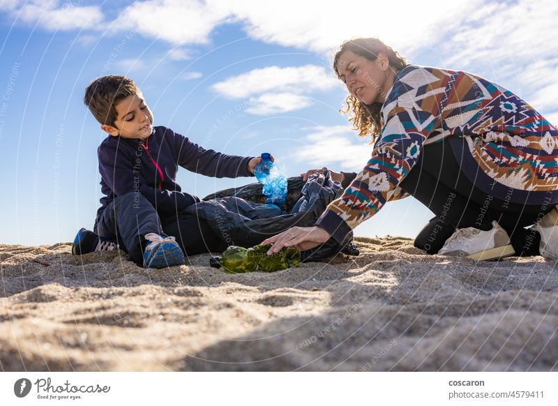 Mother and son picking plastic and garbage on the beach bottle care caucasian child clean cleanup coast collect collecting dirty ecology environment