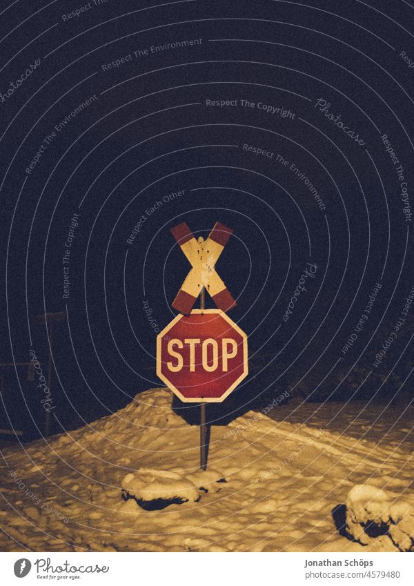 Level crossing and stop sign in the snow at night Snow Night Lantern Lighting vintage Retro Dark Evening Exterior shot Calm Deserted Winter Street out Town
