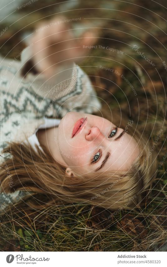Young woman lying on grass in nature knitted sweater relax rest calm harmony tranquil autumn serene peaceful warm comfort natural idyllic season meadow dream