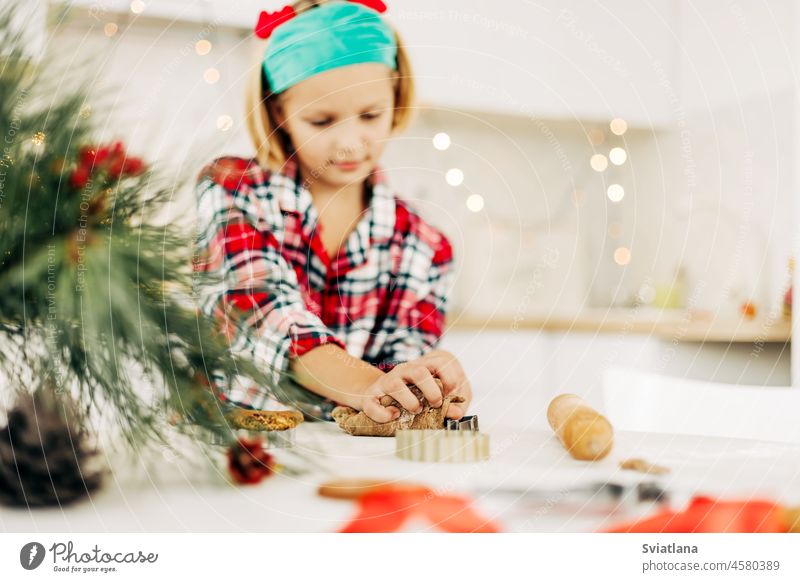 A charming girl in a Christmas costume makes Christmas cookies on Christmas Eve or New Year's Eve. Family tradition, preparation for Christmas and New Year