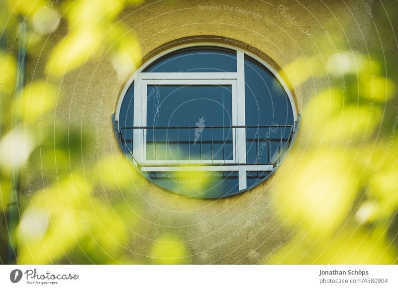 round window on yellow facade behind trees Style New building Modern downtown House building geometric Architecture architectural photography