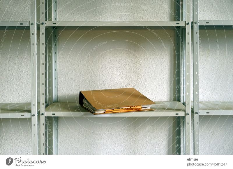 On a dusty metal shelf lies a single brown file folder / inventory / retention periods of business records. Shelves File office folder Retention period
