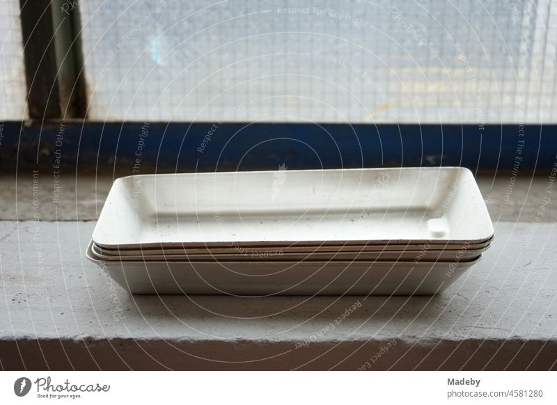 Stacked elongated bowls on the windowsill of an old factory with factory windows made of ribbed glass in the Margaretenhütte district of Gießen on the Lahn in Hesse