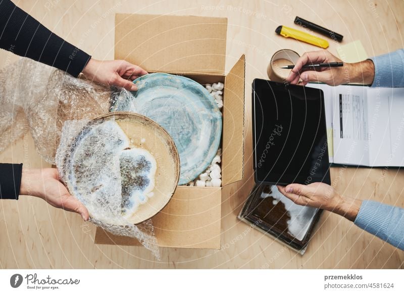 Business owner packing online order to delivery to customer. Preparing parcel box with ceramic plate product online store small business commerce shipping above