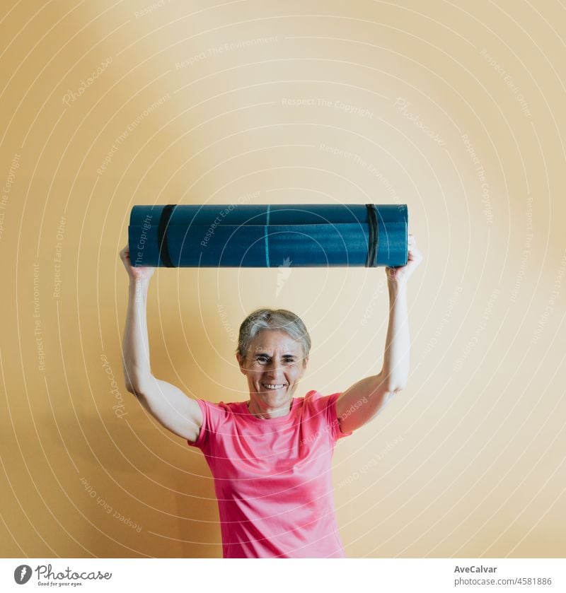 Old senior white hair woman holding a yoga mat with a colourful background. Fitness old people senior concept. Healthy life styles on senior woman to fight the arthritis