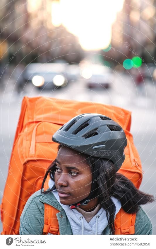 Black delivery woman on bicycle backpack service order street rider road roadway work thermo female building city african american black town lady courier