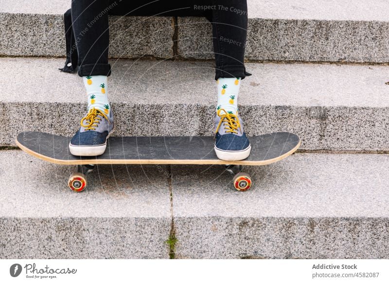 Crop skater sitting on steps putting legs on skateboard woman stair staircase sneakers trendy footwear rest urban relax sock street stone stairway put on