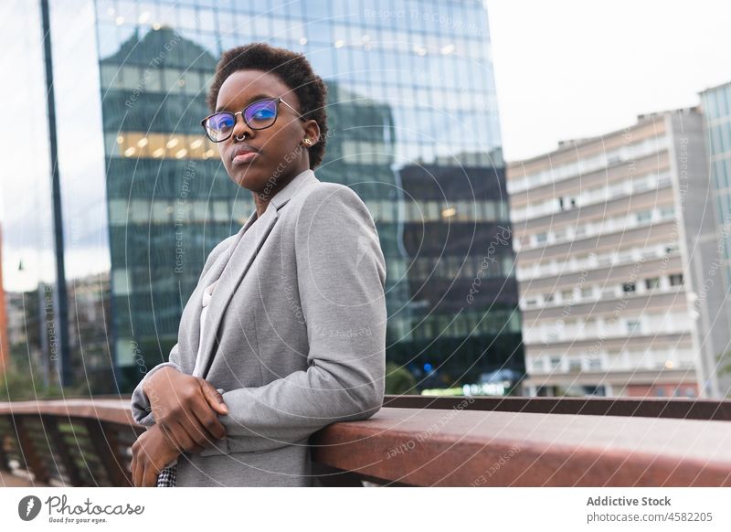 African American businesswoman in formal outfit on balcony of building railing manager city rest trendy relax urban street eyeglasses terrace modern