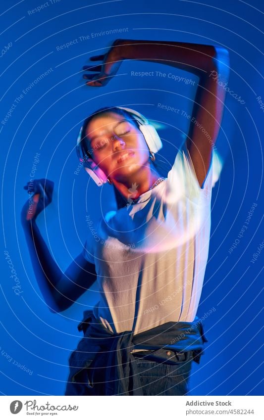 Brazilian woman in headphones in studio with shadows style trendy dance fluorescent music ultraviolet disco ball portrait song meloman eyes closed modern light