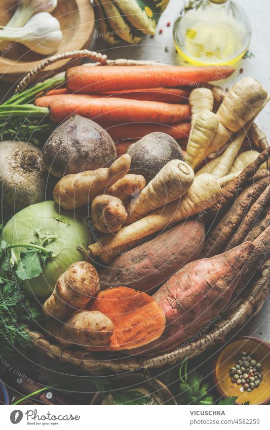 Close up of various raw organic root vegetables: Parsnip, sweet potato, carrots, kohlrabi and jerusalem artichoke on plaited tray. Healthy, sustainable lifestyle. Plastic free household. Top view