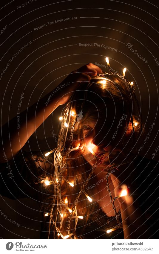 Woman with fairy lights Studio shot Shadow Young woman Artistic melancholically Adults Elegant Mysterious Kitsch Christmas tree Glittering