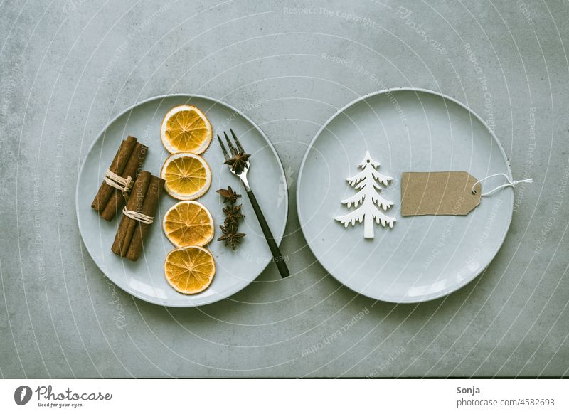 Top view of two plates with dried orange slices, cinnamon sticks and star anise on a rustic table. spices Dried Christmas Orange slice Star aniseed Plate plan