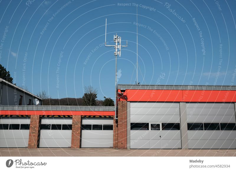 Modern fire station with industrial gates and radio mast in front of a blue sky in sunshine in Oerlinghausen near Bielefeld at the Hermannsweg in the Teutoburg Forest in East Westphalia-Lippe