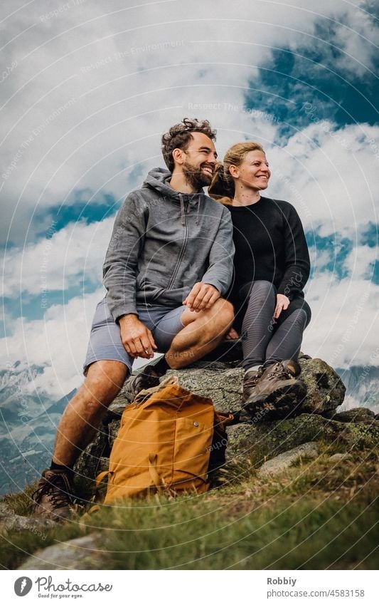 young couple on a mountain top Peak Stone Sky Clouds Hiking rest Break outlook mountain view Vantage point Smiling kind Athletic Movement vacation mountains