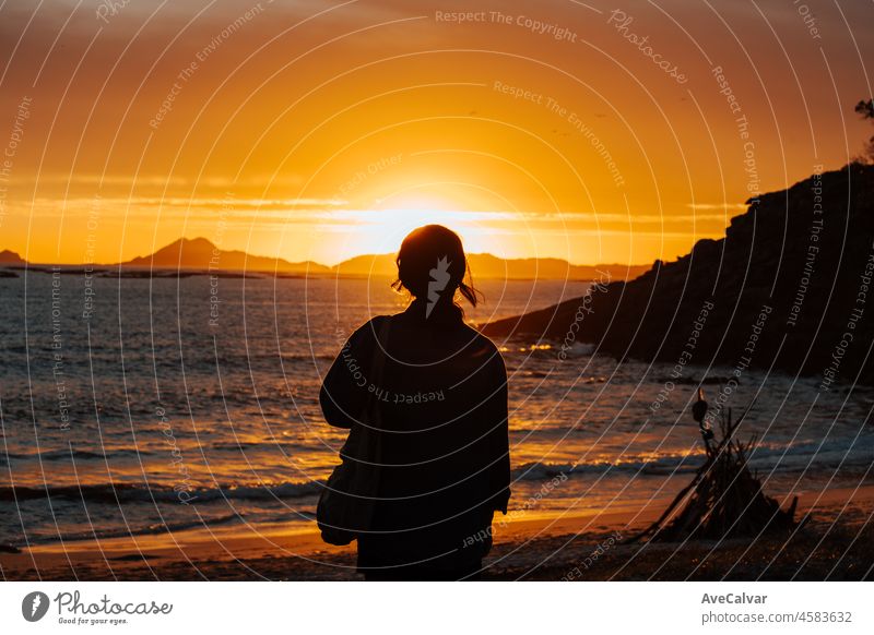 Woman stands on a beach during the sunset and looking at the islands. Young traveling woman a hipster travel. Mental health relax and thinking about the future. Freedom, travel, vacation