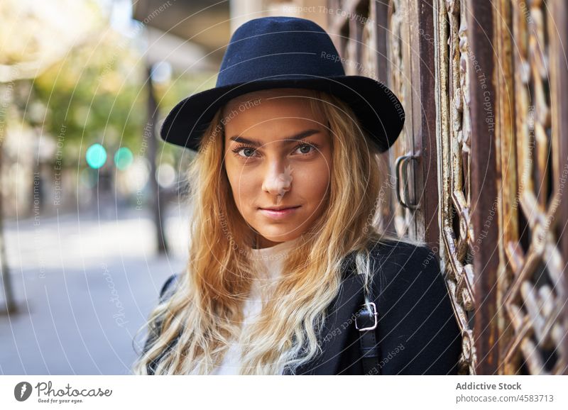 Young woman in hat and coat leaning on ornamental gate door building gateway style aged architecture fashion street old trendy town house outfit city entrance