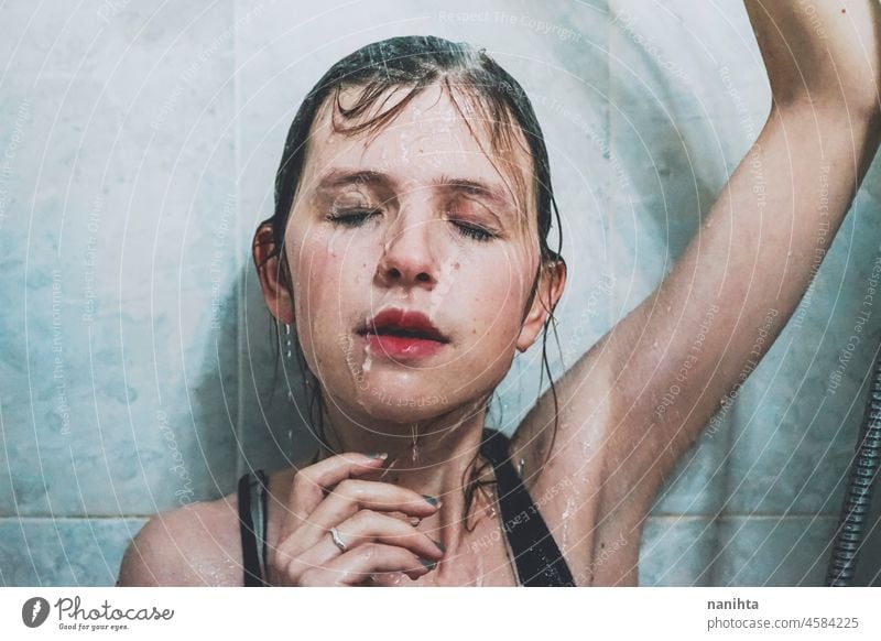 Artistic portrait of a young woman under shower water attractive fresh art artist face wet close natural real pretty long hair sensual sexy make up bath