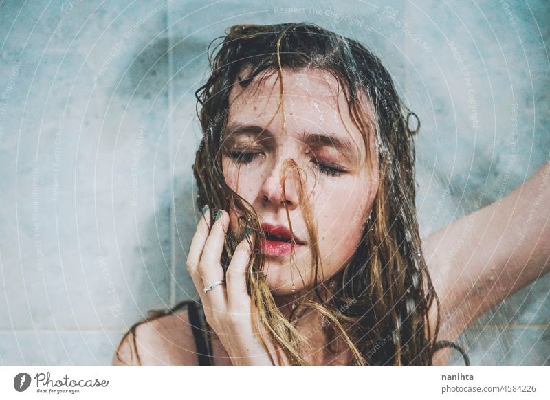 Artistic portrait of a young woman under shower water attractive fresh art artist face wet close natural real pretty long hair sensual sexy make up bath